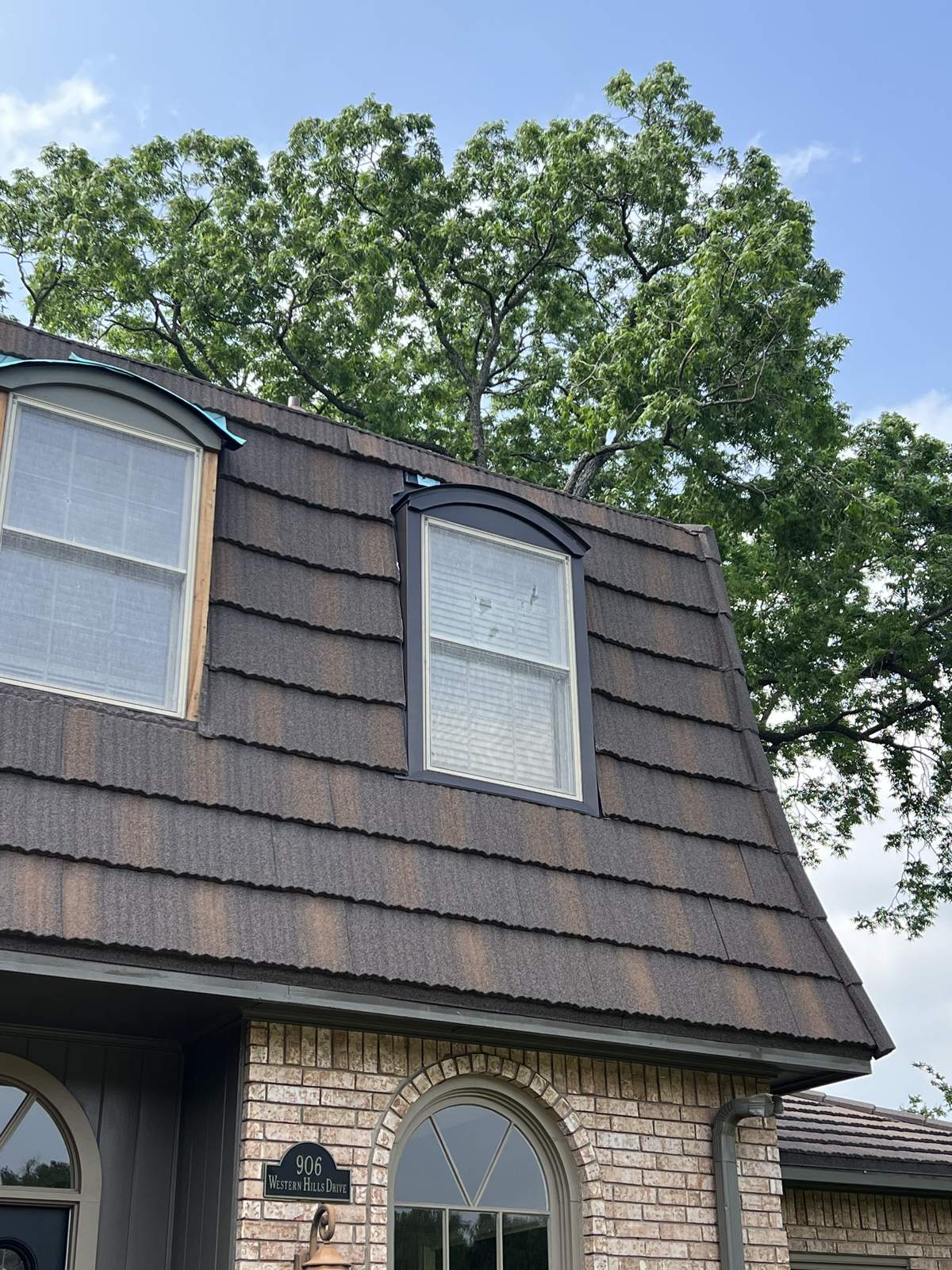 The finished stone-coated steel roof with dormers on a brick home